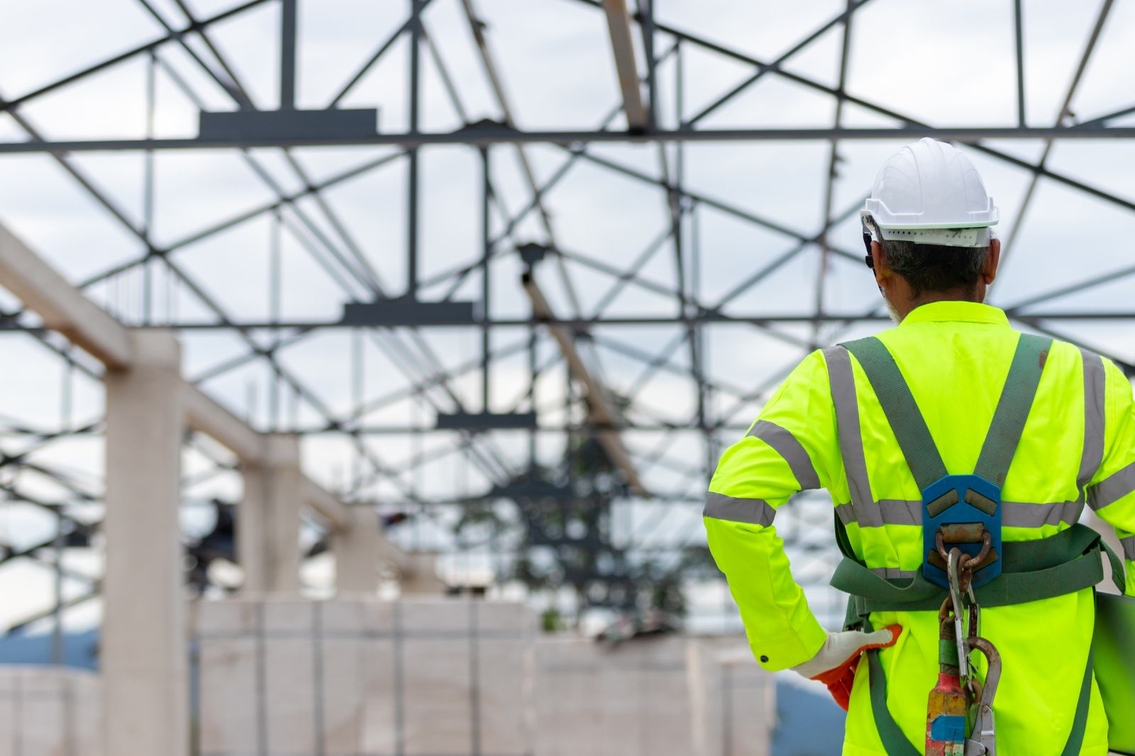 Construction worker in safety harness inspecting steel framing structure in Stockton CA